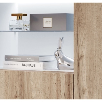 Frasco de perfume Dolce & Gabbana, caixa AERIN, livros e figura decorativa de coelho prateado numa prateleira