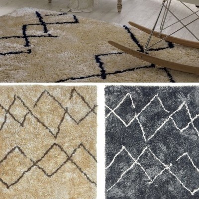 Três tapetes felpudos com padrões de losangos em creme, bege e cinza escuro, com cadeira de madeira ao lado