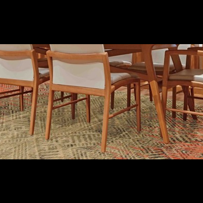 Mesa de jantar em madeira clara com cadeiras estofadas em branco sobre tapete colorido