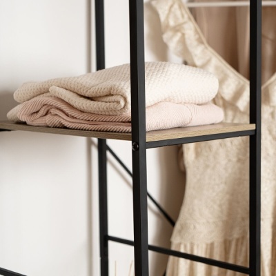 Prateleira preta com mantas creme e rosa e vestido rendado creme