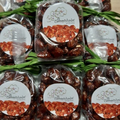 Pacotes de amêndoas caramelizadas com etiquetas brancas e folhas verdes ao redor