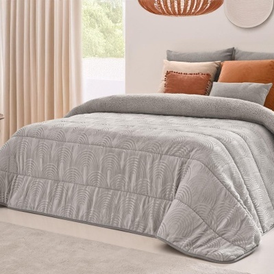 Cama com edredão cinza e almofadas em ambiente acolhedor