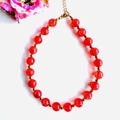 Colar de contas vermelhas com esferas douradas e fecho dourado junto a flor rosa e amarela