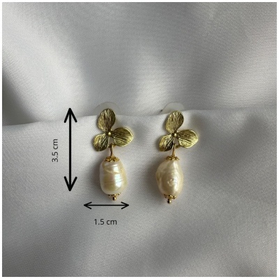 Brincos dourados com pérolas sobre tecido branco