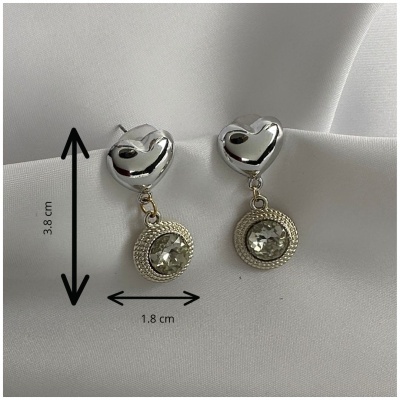Brincos prateados com coração e pendente redondo com pedra sobre tecido branco