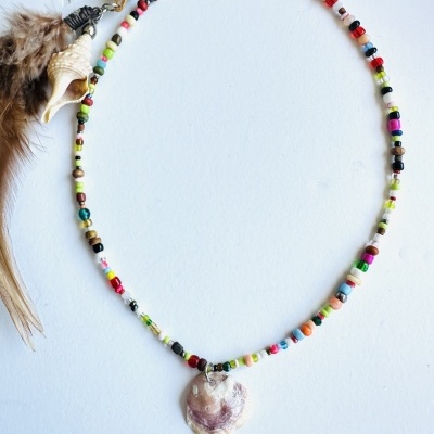 Colar com contas coloridas e pendente de concha, sobre fundo branco