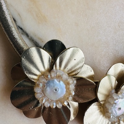 Colar com flores douradas e centro com pedras translúcidas em mármore claro