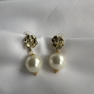 Brincos dourados com flores e pérolas sobre tecido branco