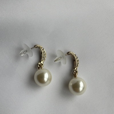 Brincos dourados com pérolas e cristais sobre tecido branco