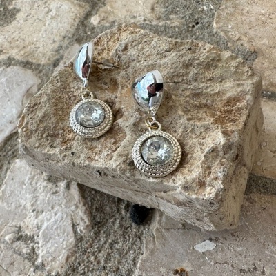 Brincos prateados pendentes com pedra brilhante em fundo de pedras rústicas