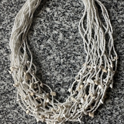 Colar de várias correntes de pérolas brancas com pedras em fundo de granito cinzento