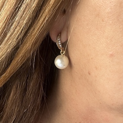 Brinco dourado com pérola e cristais na orelha de mulher com cabelo castanho claro