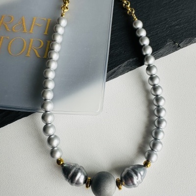 Colar de contas prateadas e douradas com saco plástico translúcido de fundo