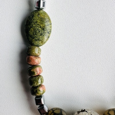 Colar com contas coloridas marmorizadas e metálicas sobre fundo branco