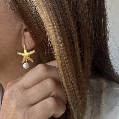 Brinco dourado de estrela-do-mar com pérola pendurada norelho de mulher