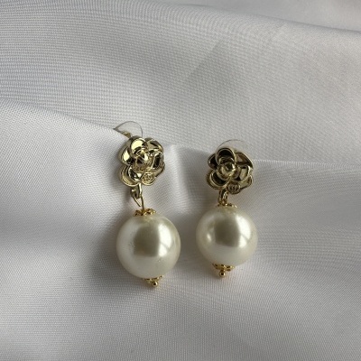 Brincos com pérolas e flores douradas sobre tecido branco