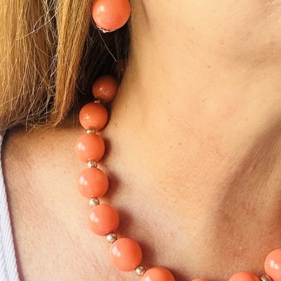 Colar e brincos de contas largas cor de coral e prata em pescoço e orelha