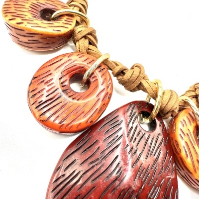 Colar artesanal com peças de resina castanhas e vermelhas com textura riscada e cordão de couro trançado