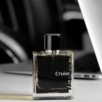 Frasco de perfume Cruise BUFFS em superfície branca com fundo de escritório desfocado