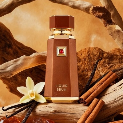 Frasco de perfume castanho com detalhes dourados e pedra vermelha, entre canela, baunilha, madeira e pedras âmbar.