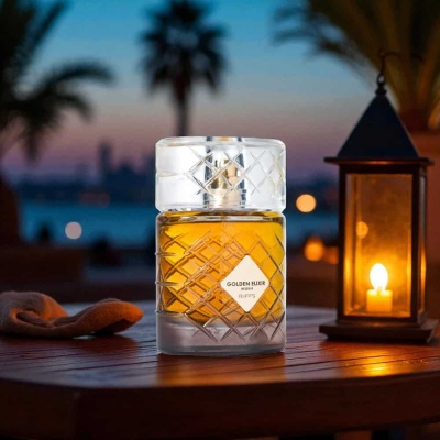 Frasco de perfume Golden Elixir sobre mesa com lanterna ao ar livre ao entardecer