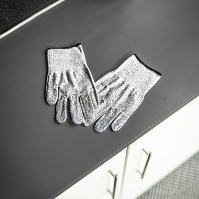 Par de luvas de malha cinza com acabamento preto sobre superfície cinza fosca