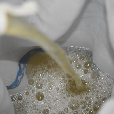 Líquido castanho a ser vertido num filtro de pano branco com borda azul