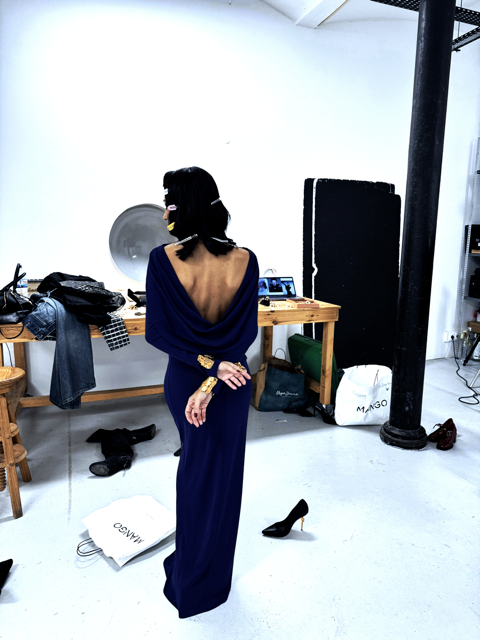 Pessoa de costas usando vestido longo azul com decote nas costas em estúdio