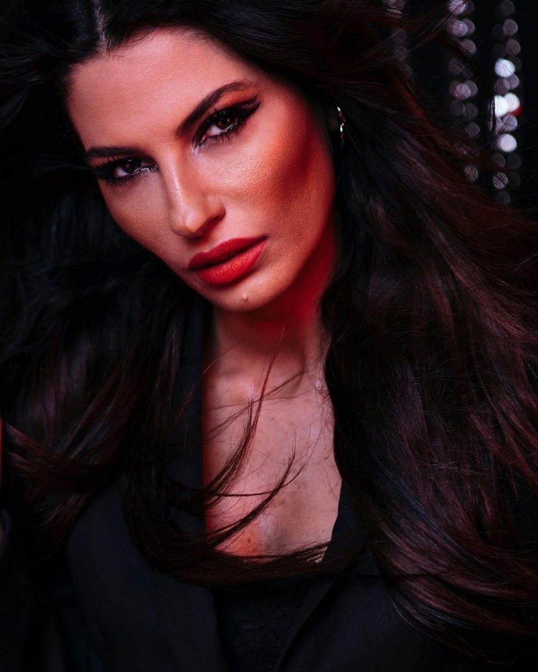 Mulher com cabelo escuro, maquilhagem vermelha e casaco preto