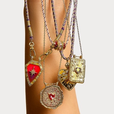 Colares dourados com pendentes vermelhos e detalhes brilhantes sobre braço