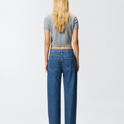 Mulher de costas com camisola cinzenta e calças de ganga azuis