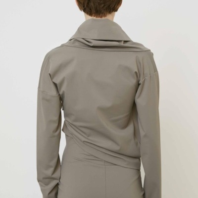 Vista traseira de mulher com camisa e saia cinza bege.