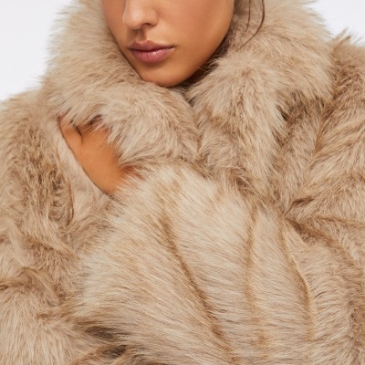 Casaco de pelo sintético bege claro com textura felpuda em fundo branco