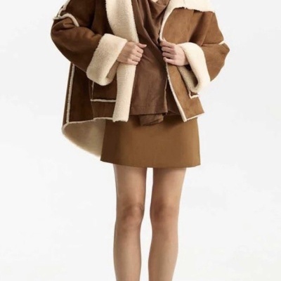 Pessoa com casaco castanho e creme, vestido castanho, botas castanhas e óculos escuros