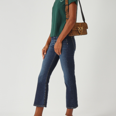 mulher com t-shirt verde, jeans azuis, sapatilhas brancas com padrão animal e bolsa com padrão leopardo