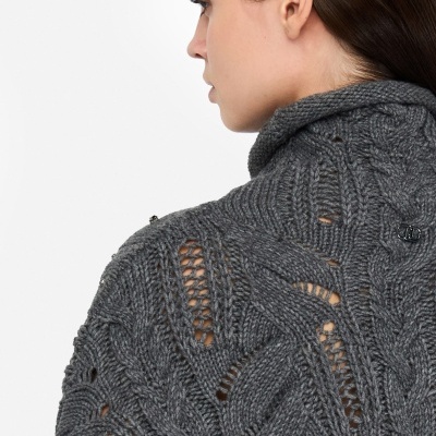 Casaco de malha cinzento com padrão trançado e detalhes vazados visto de lado