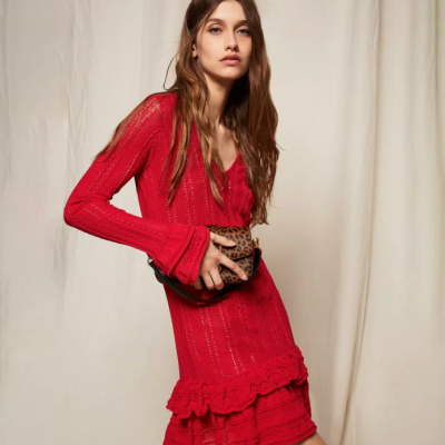 Mulher com vestido vermelho de malha e mala animal print em fundo bege