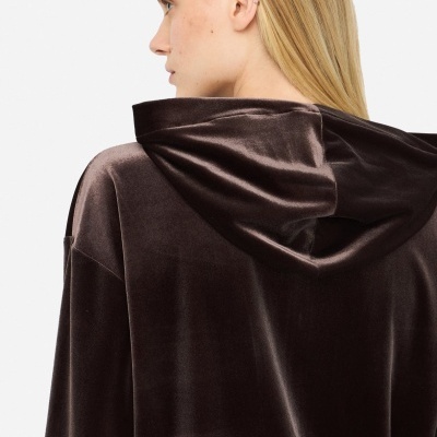 Casaco castanho escuro de veludo com capuz, visto de trás num modelo com cabelo loiro.