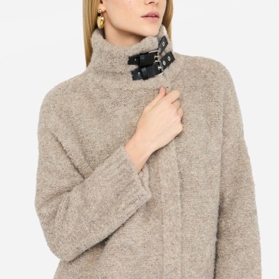 Casaco bege felpudo com gola alta e fivelas pretas em modelo feminino