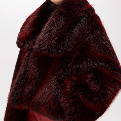 Casaco de pelo vermelho escuro e preto com textura espessa usado por mulher