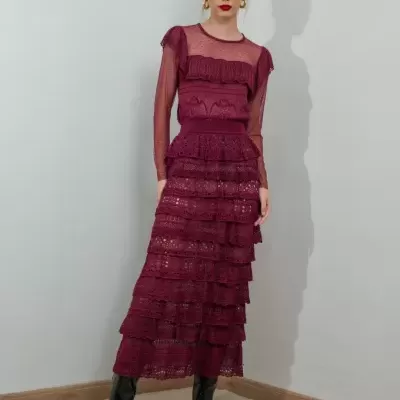 Mulher a vestir vestido longo de renda vinho com camadas e mangas transparentes com botas pretas
