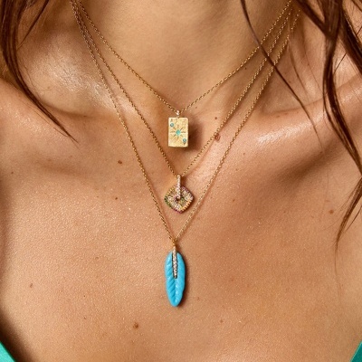 Colar triplo dourado com pendentes multicoloridos usado por mulher com vestido verde