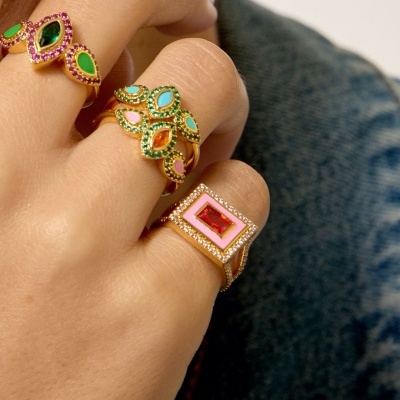 Mão com anéis dourados coloridos com pedras e cristais