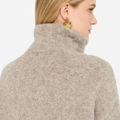 Pessoa com casaco bege felpudo e brinco dourado de coração