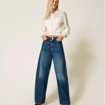 Calças de ganga largas azuis com cinto castanho e camisola branca com padrão rendado