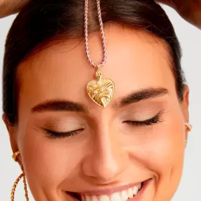 Colar dourado com pendente em forma de coração na testa de mulher sorridente