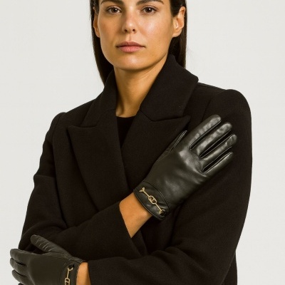 Mulher com casaco preto e luvas pretas de pele com detalhe dourado.