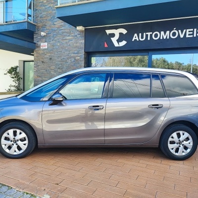 Carro familiar cinza metálico em frente a loja RC AUTOMÓVEIS