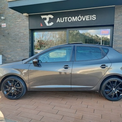 Carro cinzento metálico de 5 portas com jantes pretas e loja RC AUTOMÓVEIS em fundo