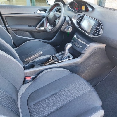 Interior de carro com bancos cinza, volante de couro e painel com ecrã tátil